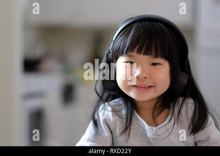 A young asian girl enjoying listening to music on her headphone Stock Photo