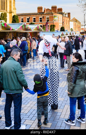 Super-sized chef (man on stilts) shares high five with small boy in crowd - Wakefield Food, Drink & Rhubarb Festival 2019, Yorkshire, England, UK. Stock Photo