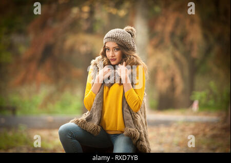 Happy Portrait fashion of a beautiful young Caucasian woman with a red cap and scarf and yellow pullover in autumn park,red green yellow threes. Stock Photo