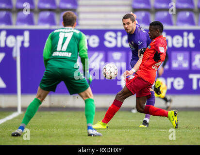 Aue, Germany. 09th Mar, 2019. 09 March 2019, Saxony, Aue: Soccer: 2nd Bundesliga, Erzgebirge Aue - SC Paderborn 07, 25th matchday, in the Sparkassen-Erzgebirgsstadion. Aues Pascal Testroet (M) plays the ball between Paderborn's goalkeeper Leopold Zingerle (l) and Jamilu Collins as a template to the goal to 1-0 through. Credit: dpa picture alliance/Alamy Live News Stock Photo