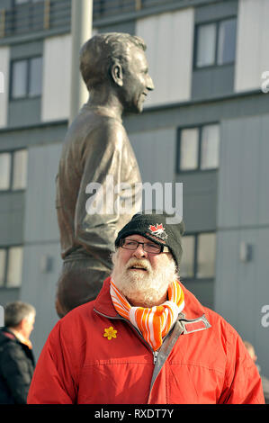 A Blackpool fan stands by the statue of the late Jimmy Armfield outside the clubs Bloomfield road ground Stock Photo