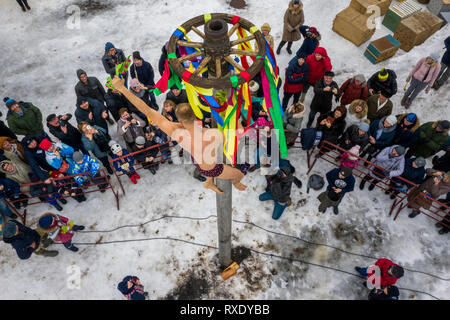 Suzdal, Russia. 9th  March, 2019: A man climbs up a pole to get the prize as he celebrates the Maslenitsa (Pancake week) festival in Suzdal town, Russia. Maslenitsa is an Eastern Slavic religious and folk holiday, celebrated during the last week before Great Lent Stock Photo