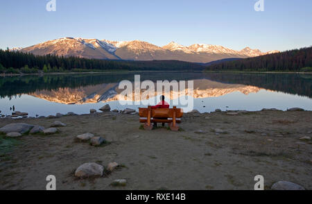 Middle age male sitting on bench looking Patricia Lake, Jasper National Park, Alberta, Canada. Stock Photo
