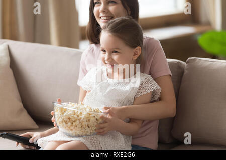 Happy family mom with cute kid daughter watching tv together Stock Photo