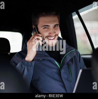 business man uses a laptop and mobile phone sitting in the car Stock Photo