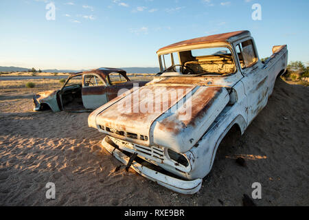 Discarded old cars sit by the road in the south of Namibia at Solitaire. Stock Photo