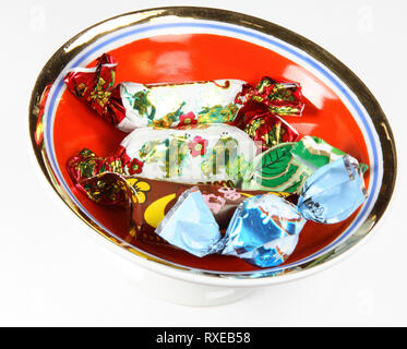 set of candies in sweet wrapper on red saucer Stock Photo