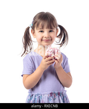 Four-year-old girl in a purple t-shirt eat donut.The girl's hair is tied in tails. Isolated on white background. Stock Photo