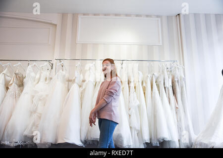 A pretty Red haired girl is Wedding Dress shopping by herself in a beautiful shop- she is trying on dresses and shoes Stock Photo