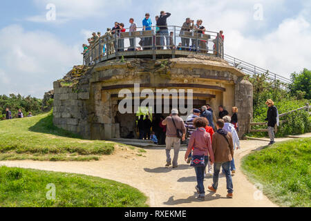 Visitors climb on one of the concrete gun positions, Pointe du Hoc site, part of the D-Day landing at Omaha Beach, Normandy, France. Stock Photo
