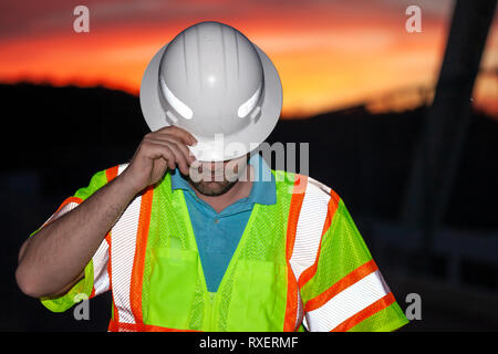 Construction worker wearing protection clothing with hard hat, partially covering his face Stock Photo