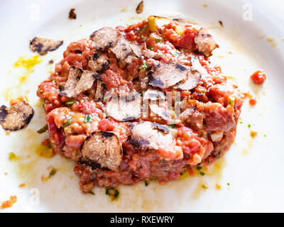 beef steak tartare with raw egg and truffle close up on white plate in Lombardy Stock Photo