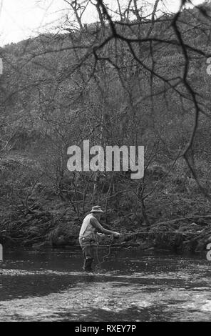 A fly fisherman on the West Dart River at Hexworthy Bridge on Dartmoor, Devon, UK.  Black and white film photograph, circa 1994 Stock Photo