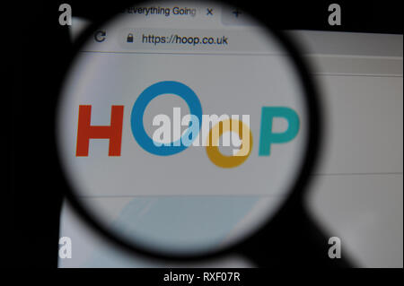 The Hoop website seen through a magnifying glass. Hoop is an app in which parents can book childrens activities. Stock Photo