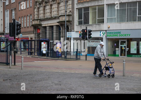 Old man walking with mobility walker through town centre Stock Photo