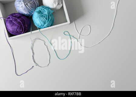 Love word from colorful cotton threads from knitting yarns in white box with copy space under it on white background. Handmade with love. Stock Photo