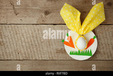 Easter decorations children table. Easter bunny holding a napkin on plate on vintage wooden background. Children's Art Project, needlework, crafts for Stock Photo