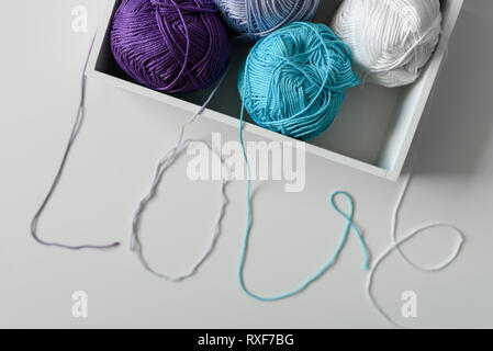 Idea for love word designed from cotton threads from yarn balls in white box. Stock Photo