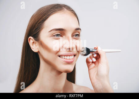 Professional make up artist applying on woman fashion model cheeks powder or consiller using brush Stock Photo