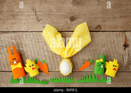 Row of funny easter bunnies and easter egg in nupkin on wooden background, springtime concept, copy space Stock Photo