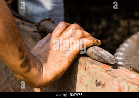 Workers at a shipyard in Dhaka Bangladesh holding a chisel with their oil-smeared hands Stock Photo