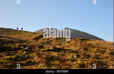 Two Hikers Walking Towards the Wainwright Catstycam from the Youth Hostel in Glenridding in the Lake District National Park,  Cumbria, England, UK. Stock Photo