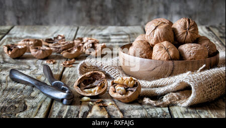 Walnuts in a bowl with nutcracker and cracked nuts Stock Photo