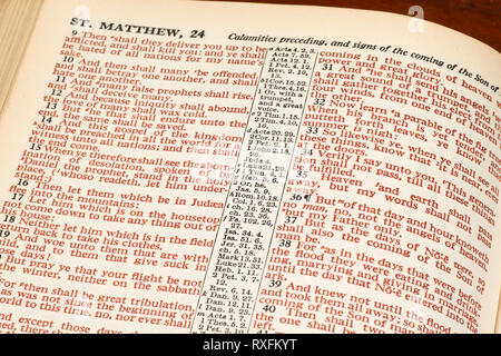 Horizontal close-up shot of an open Bible show Matthew 24 in red print. Stock Photo