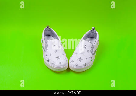 Women or teenage fashion, white slipons, Stylish shoes on green background. Beauty and fashion concept. Flat lay, Top view copy space. Stock Photo