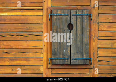 Log Wall Texture with Closed Wooden Window Shutters. Log House Background Stock Photo