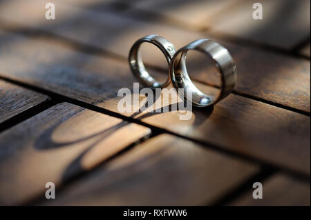 two steel rings on wooden table casting elongated shadows, with the inscription Stainless steel Stock Photo