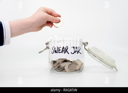 Childs hand putting coin into swear jar Stock Photo