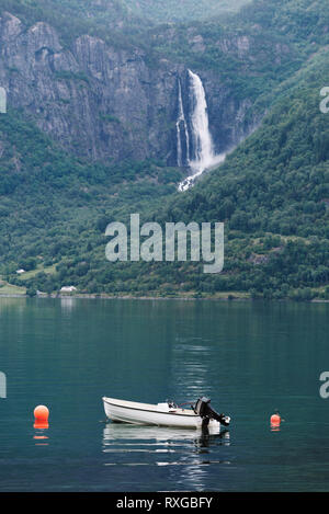 White boat in a Norwegian fjord. View of Feigumfossen waterfall 