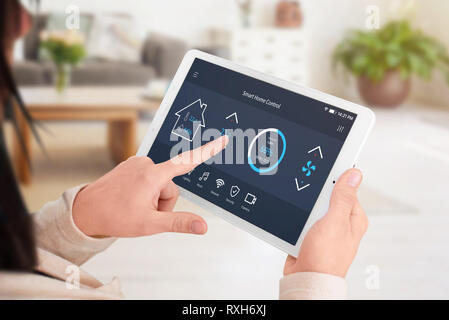 Modern software to home control on tablet display. Woman control temperature in living room. Close-up. Stock Photo