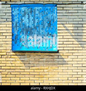 Perforated Steel Sheet with Peeling Blue Paint in Window. Abstract Background of Aged Brick Wall Stock Photo