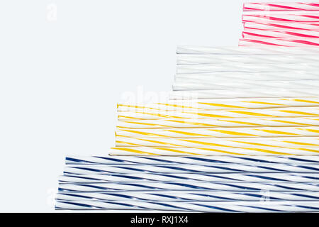 Blue, yellow, white and red stripes of thin candles on a white background, concept Stock Photo