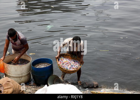 Recycled plastic chips washing in the polluted water of Buriganga River. Dhaka, Bangladesh. Stock Photo