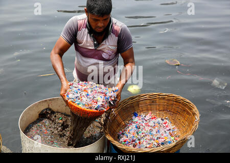 Recycled plastic chips washing in the polluted water of Buriganga River. Dhaka, Bangladesh. Stock Photo