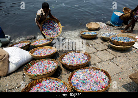 Recycled plastic chips washing in the polluted water of Buriganga River. Dhaka, Bangladesh. Stock Photo