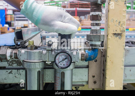 The hand of technician adjust the pressure setting of the wind on regulator. In the pneumatic system Stock Photo