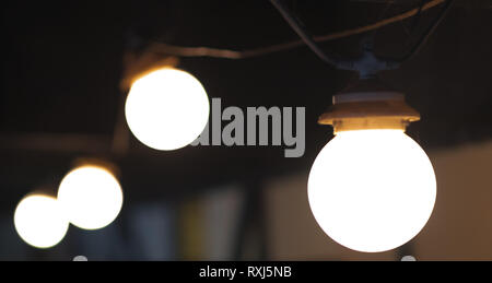 A group of 4 light bulbs in a line on a dark background Stock Photo