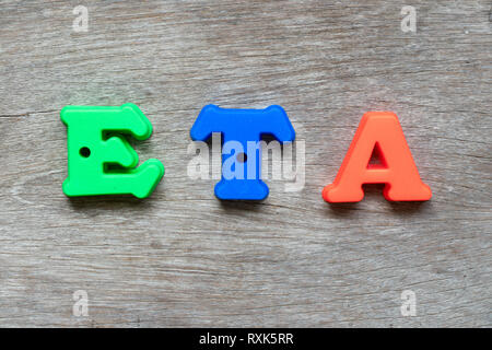 Colorful plastic alphabet in word  (Abbreviation of Estimated Time of Arrival) on wood background Stock Photo