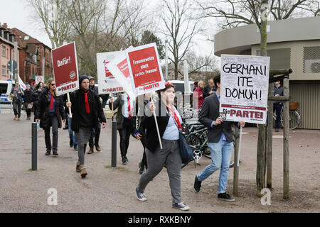 Landau, Germany. 9th March 2019. Members of the party Die Partei carry posters to the protest. One reads 'Germane ite domum',(Germans go home in Latin), a reference to the movie 'Monty Python's Life of Brian' Around 80 people from right-wing organisations protested in the city of Landau in Palatinate against the German government and migrants. They also adopted the yellow vests from the French yellow vest protest movement. They were confronted by several hundred anti Credit: PACIFIC PRESS/Alamy Live News Stock Photo