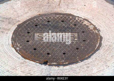 Weathered sewer manhole cover on a road Stock Photo