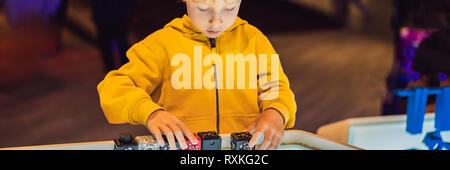 The boy plays with the electronic designer on the light table. BANNER, LONG FORMAT Stock Photo