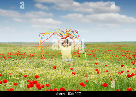 happy little girl waving with colorful ribbons on meadow in spring Stock Photo