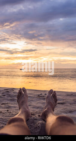 Close-up of female foot, Woman's feet walking to the sea in sunset colorful sky. Vacation, traveling and freedom concept.- Vintage tone VERTICAL Stock Photo