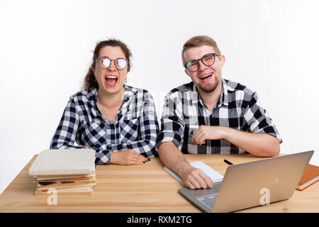 Nerds, geek, bespectacled and funny people concept - funny student couple in glasses sitting at the table. Stock Photo