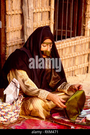 Arab folklore and history with an Emirati Bedouin lady demonstrating basket weaving during the Dubai Trade Festival in the United Arab Emirates Stock Photo