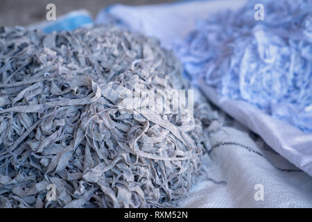 Fabric scraps, old clothing and textiles are cut into strips waiting for recycle Stock Photo
